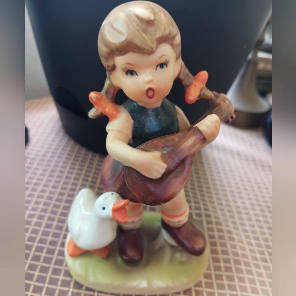 Hummel like figurine girl w/ goose playing guitar. Perfect condition..